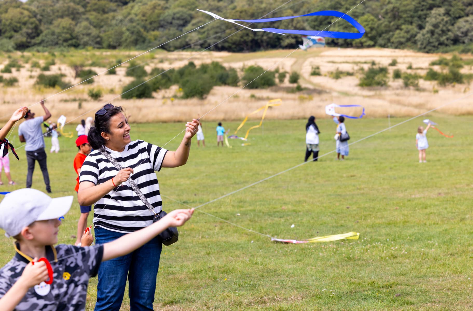 A woman and a child both flying brightly coloured kites in a field