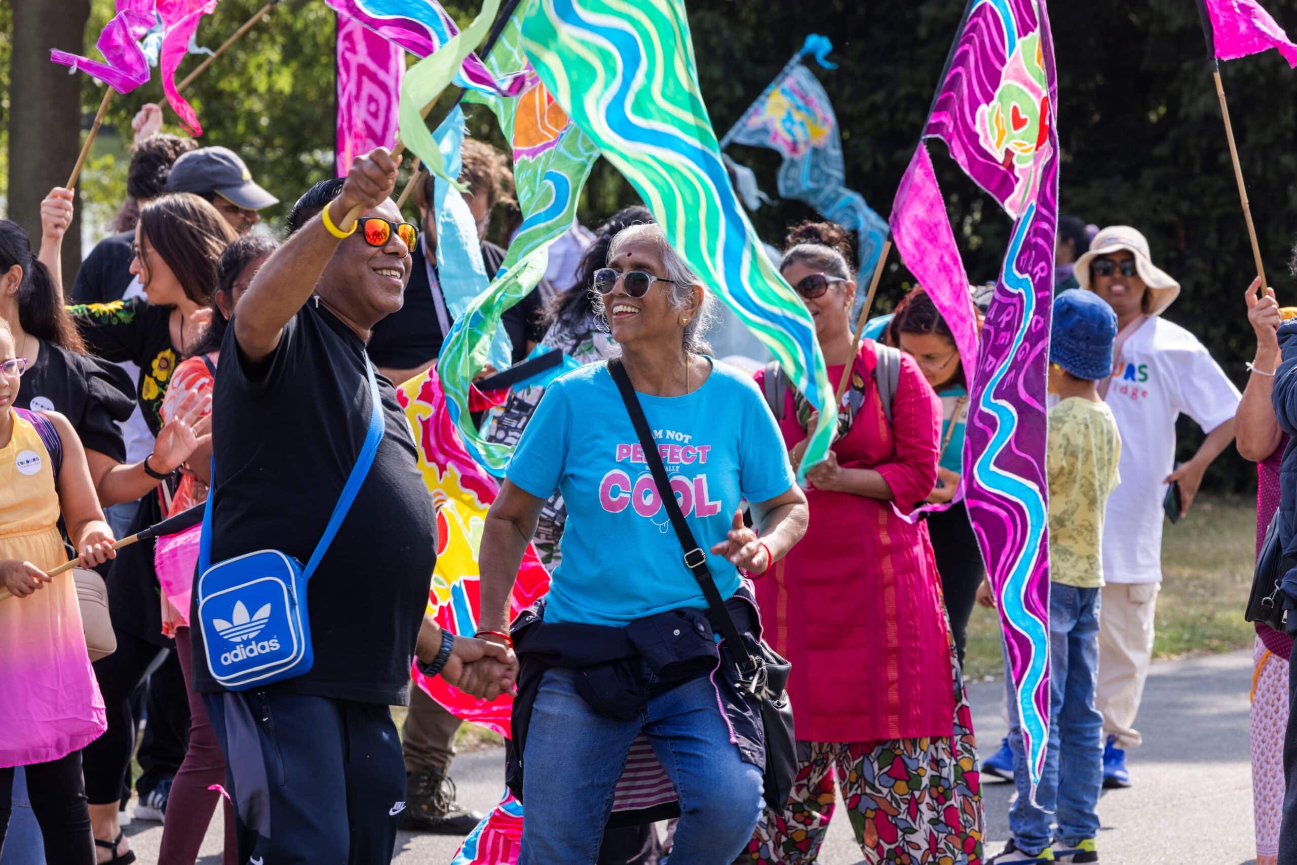 People dancing in the sunshine with colourful flags
